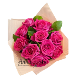 Ramo de doce rosas de color rosa claro con hojas verdes decorativas, envuelto en papel artesanal con un lazo elegante.