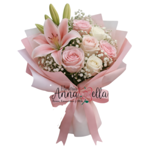 Ramo floral compuesto por tres rosas rosadas, tres rosas blancas y dos grandes flores de lilium blanco con capullos, rodeado de follaje verde y envuelto en papel decorativo premium.