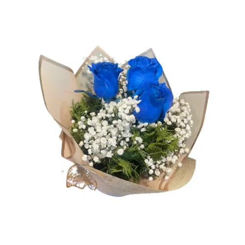 Un ramo de flores que contiene tres rosas de color azul brillante rodeadas por pequeñas flores blancas de gypsophila y follaje verde, envuelto en papel decorativo beige con un lazo dorado en la base sobre un fondo blanco.